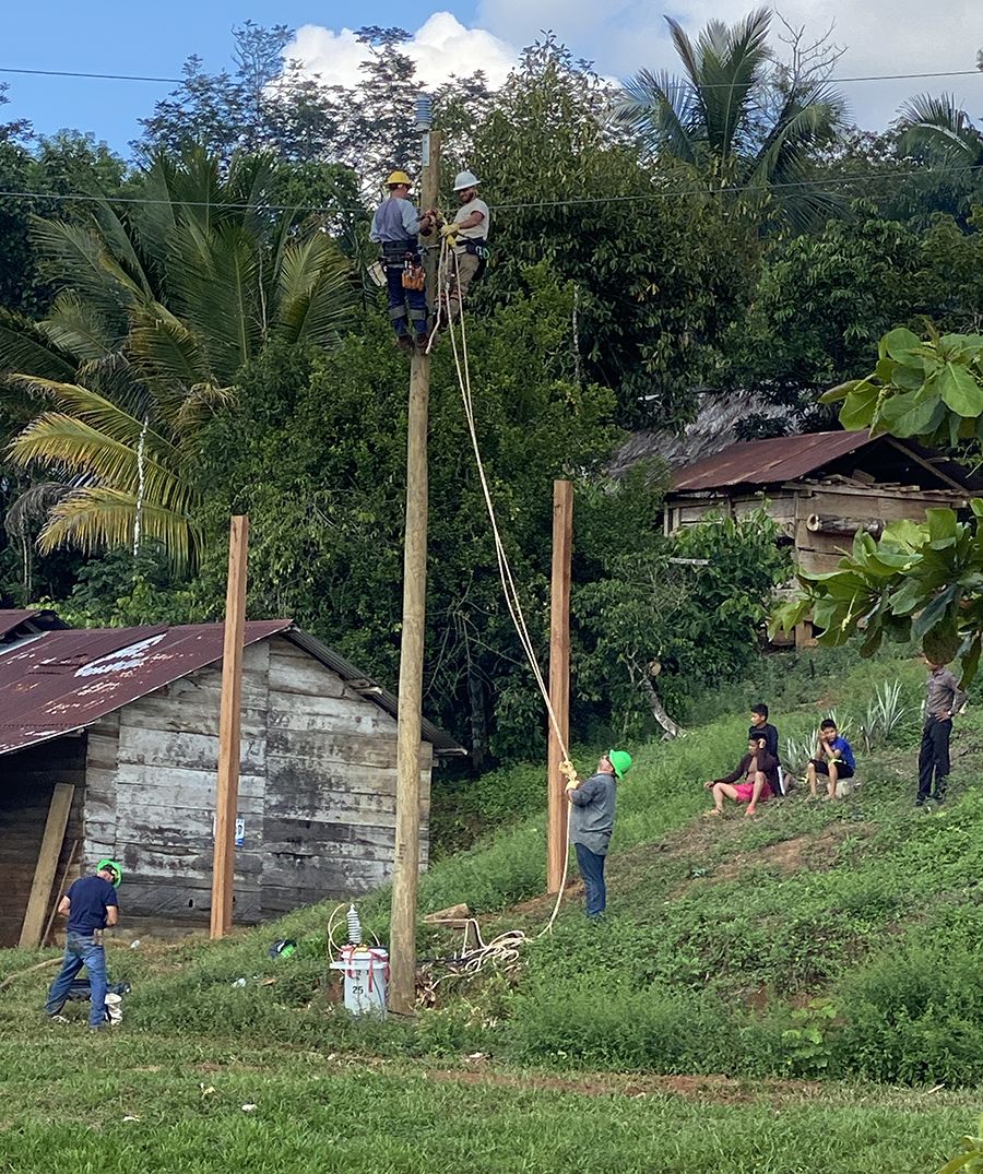 Lineworkers from SMECO and other utilities work on a pole while Santa Isabel villagers watch