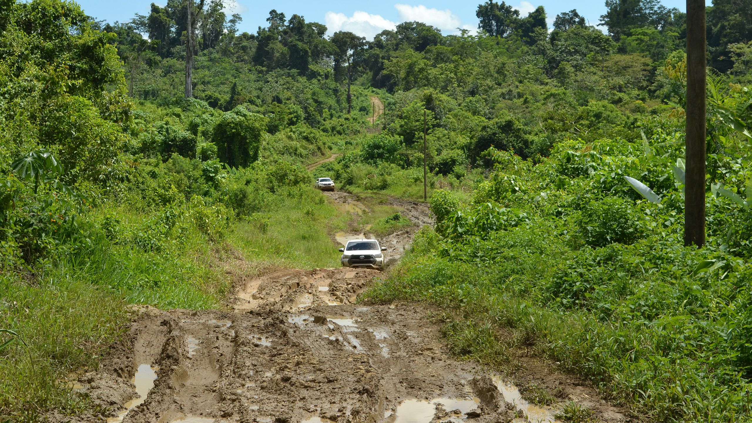 Utility pickup trucks navigating muddy road